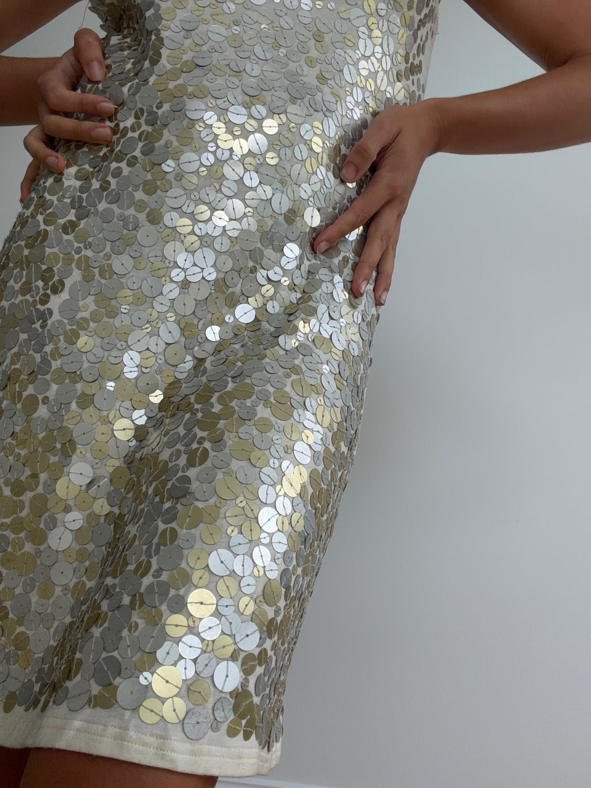 Close-up of silver-toned disc sequins over cream-toned dress fabric