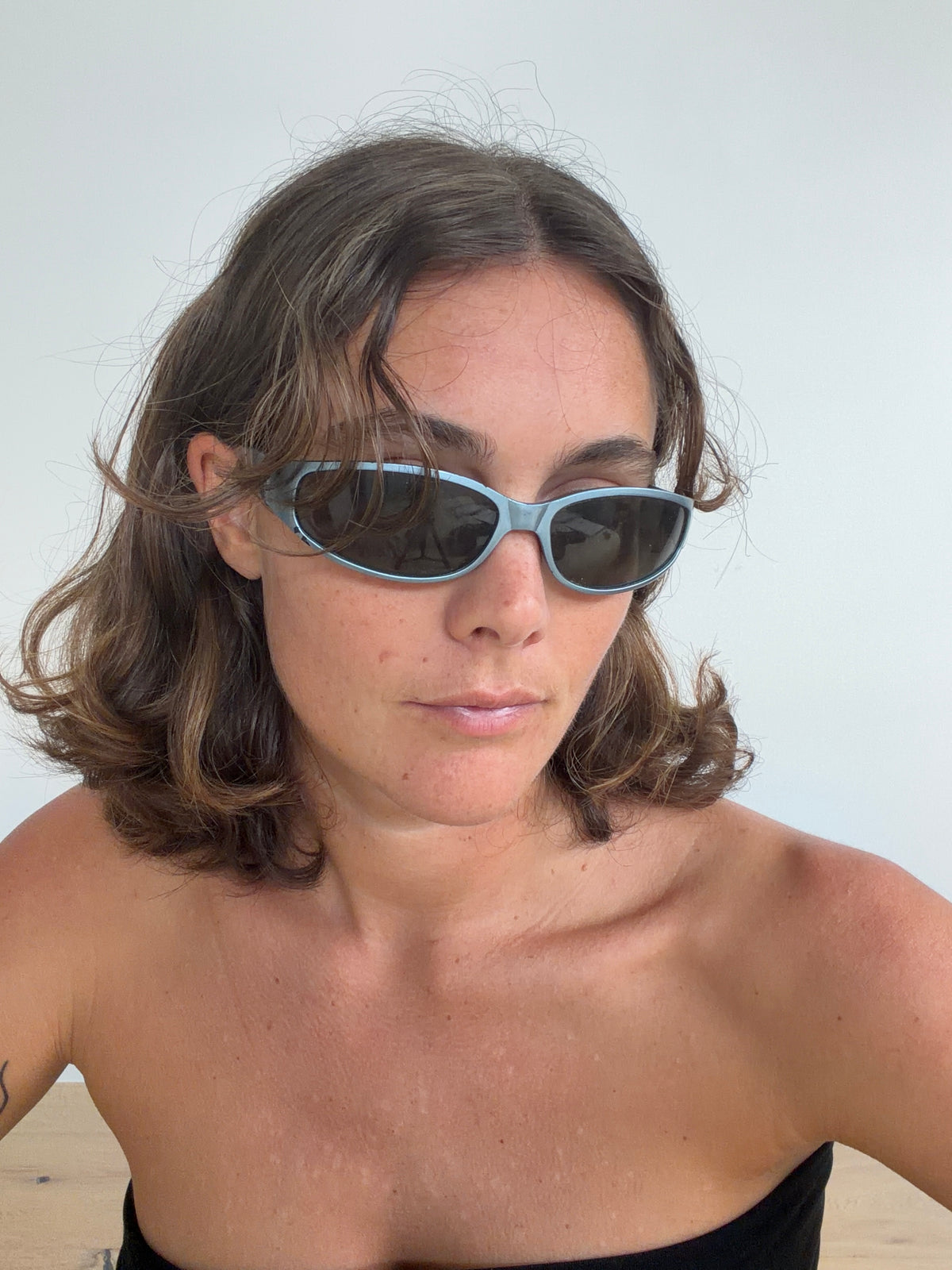 Angled view of blue-toned Y2K sunglasses showing curved frame, worn