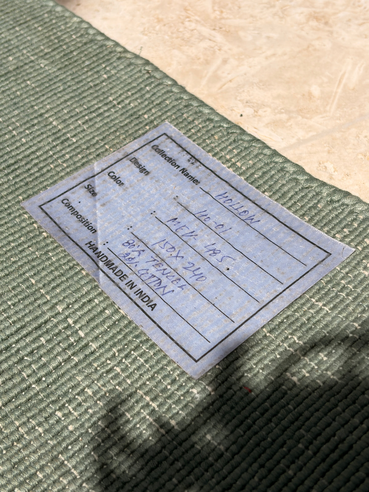 Rug backing label showing composition, dimensions and handmade in India